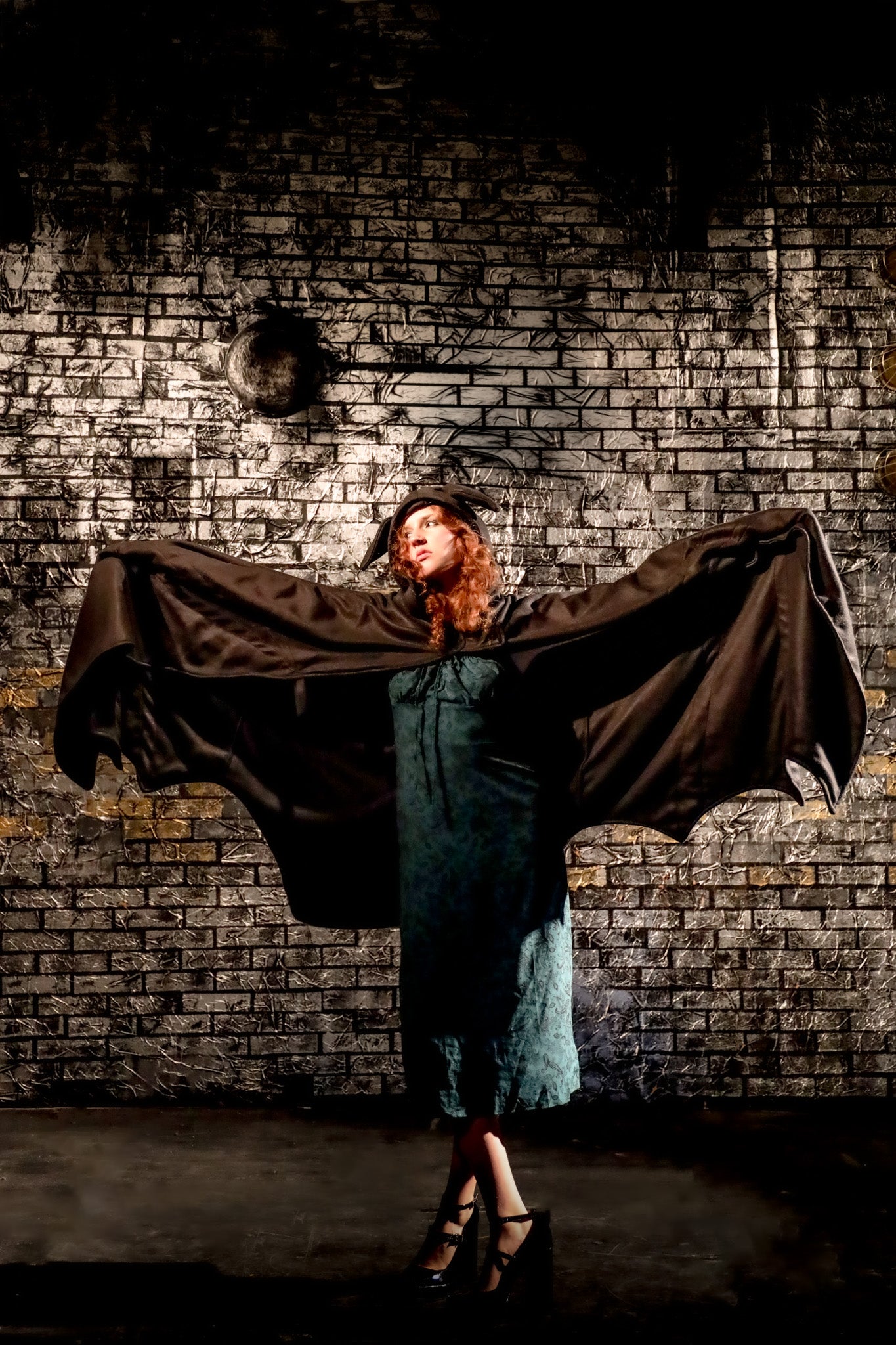 Person with a cape in front of a brick wall