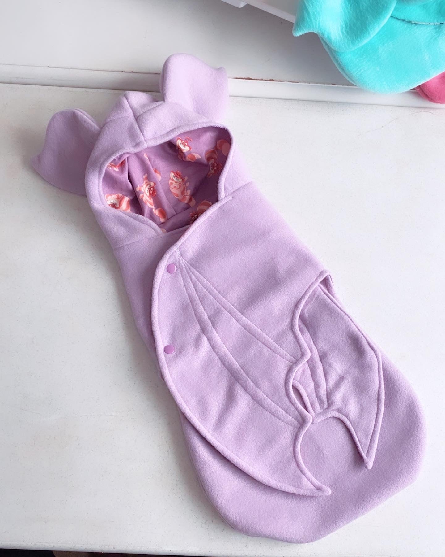 Purple baby wrap with pink interior on a white surface