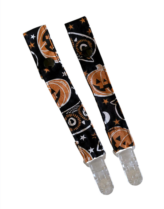 Two Halloween-themed pacifier clips on a white background