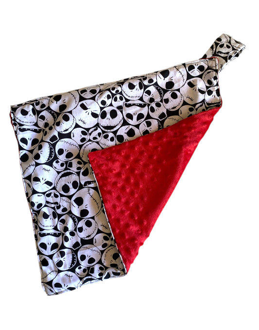 Baby blanket with skull pattern and red minky side on a white background