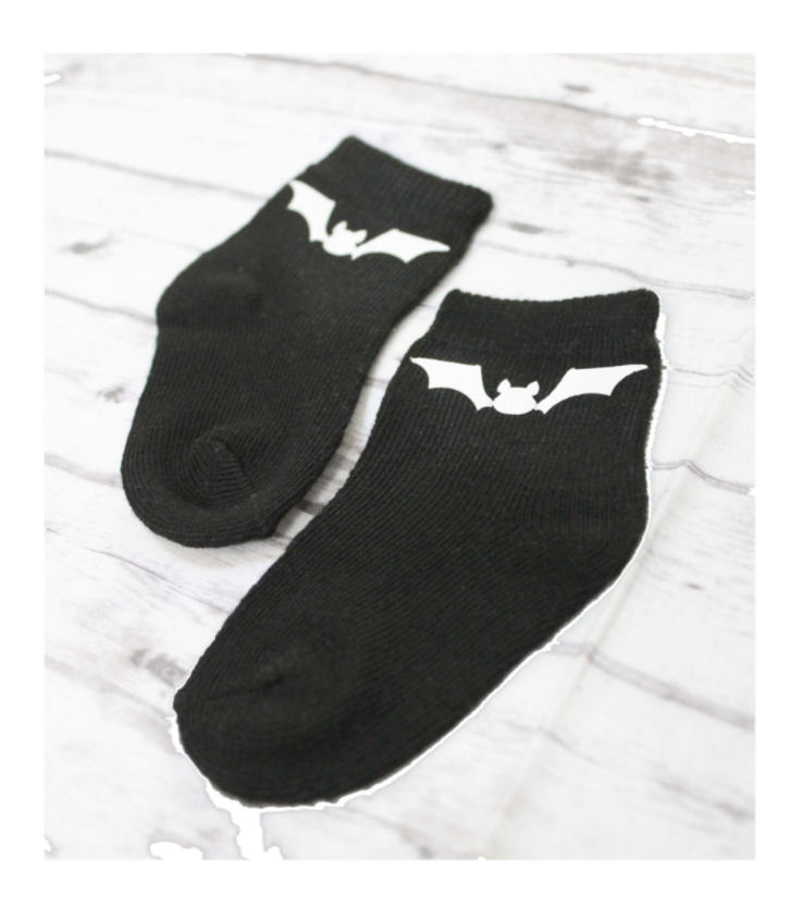 Black socks with bat design on a light wooden surface