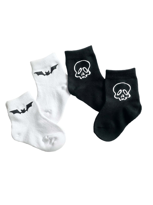Two pairs of socks with skull and bat designs on a white background