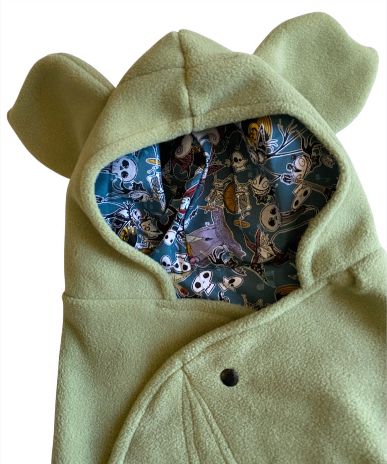 Light green hooded blanket with nightmare skull lining on a white background
